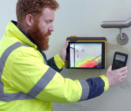Surveyor using a moisture meter and digital moisture mapping device to identify hidden damp in a property.